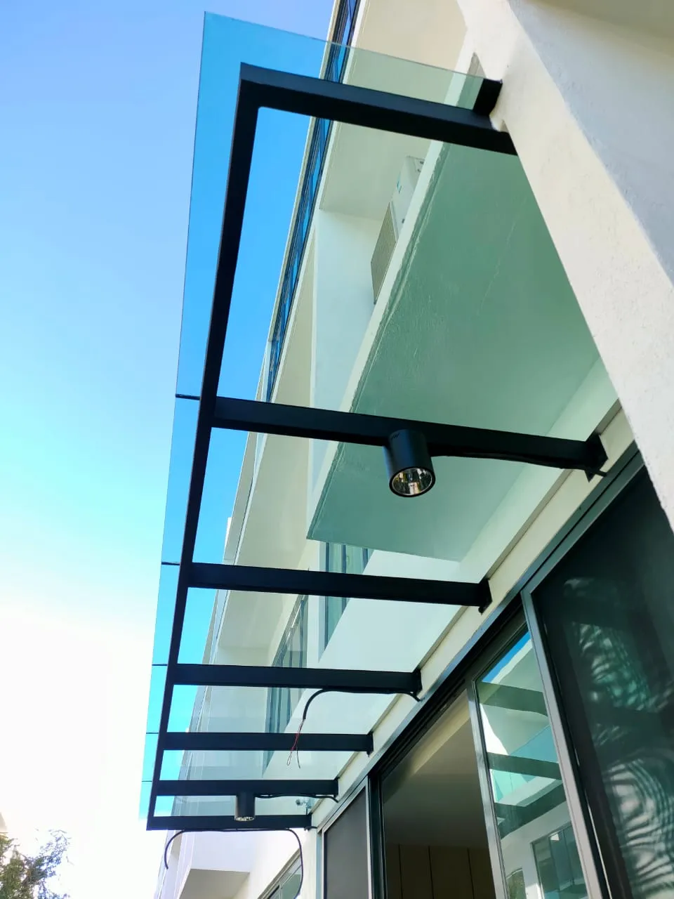 Close-up of a glass roof awning frame installed beside a sliding door